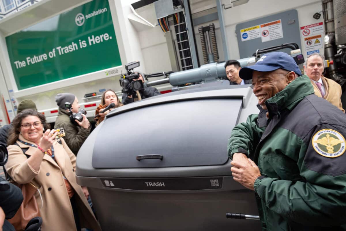 Mayor Adams and reporter with trash container