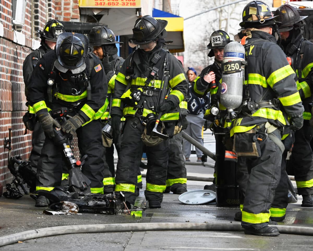 Firefighters work to removed a badly burned e-bike battery from its holding cell.