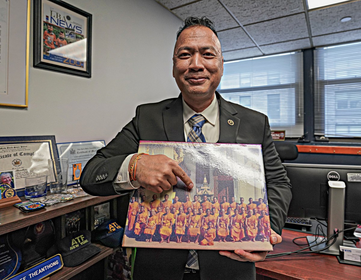 Queens NYPD Captain Tawee Theanthong pointing to photo of himself as a monk at Thai monastery
