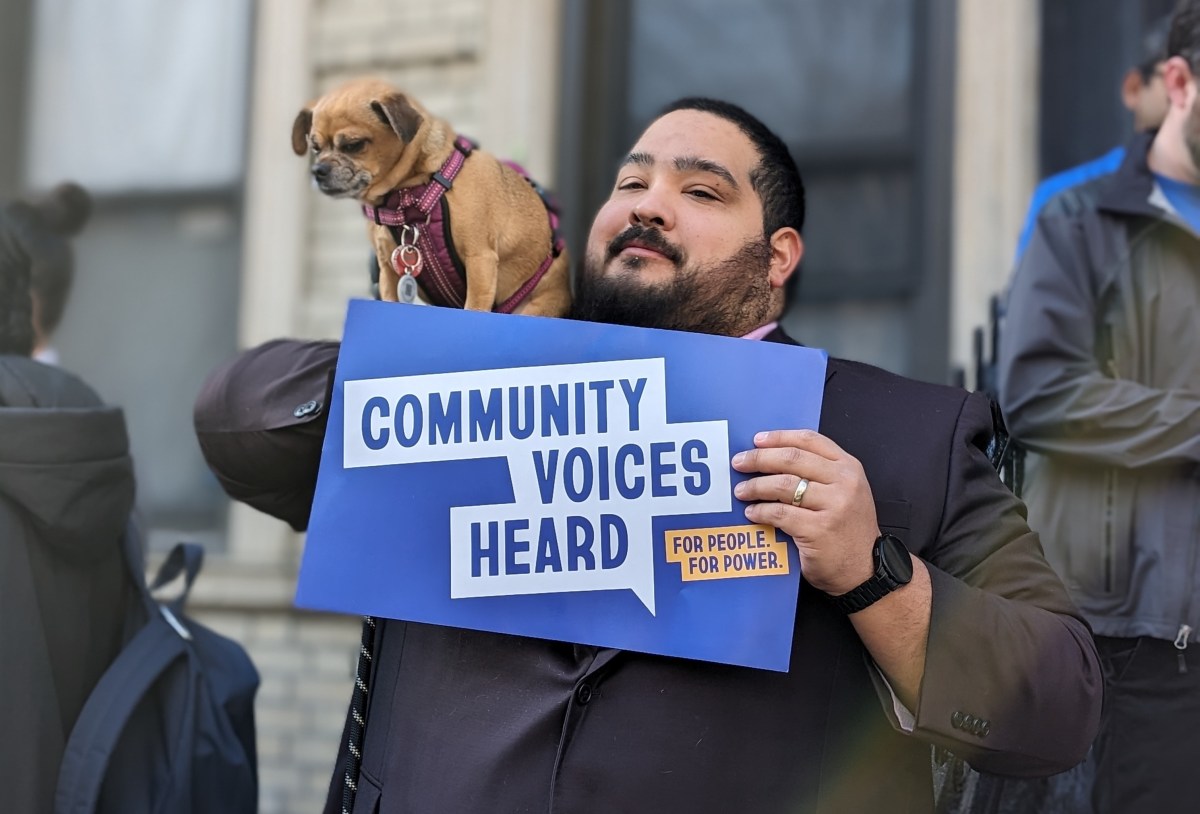 Man holding sign with dog in East Harlem