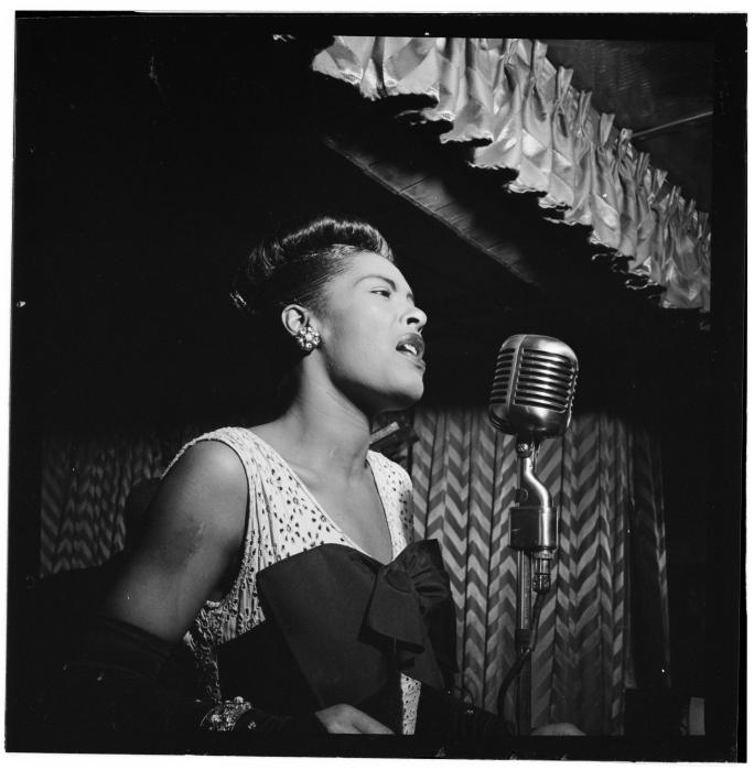historic photo of Billie Holiday, who will be honored in a public art initiative honoring influential NYC women, singing into a microphone on stage