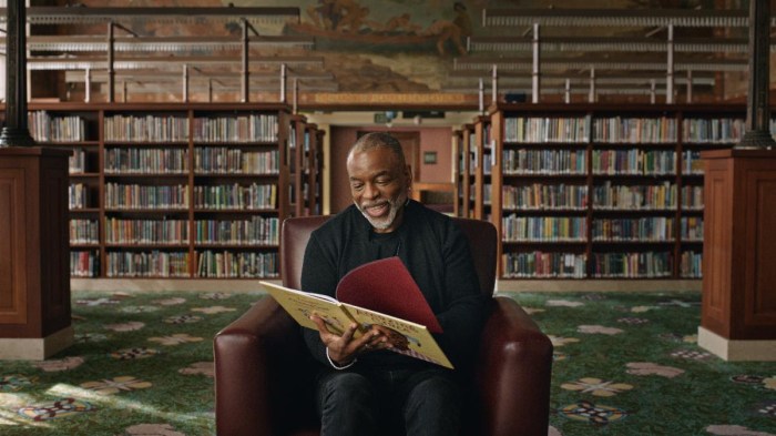 Actor LeVar Burton from Reading Rainbow in a library holding a book