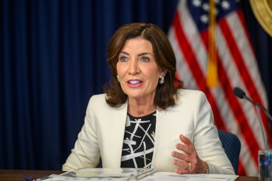 NYS Gov. Hochul at a desk with American flag behind her