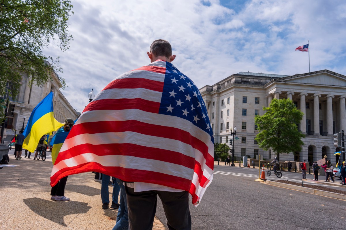 Man wearing American flag, with Ukraine flag in background, after House vote.