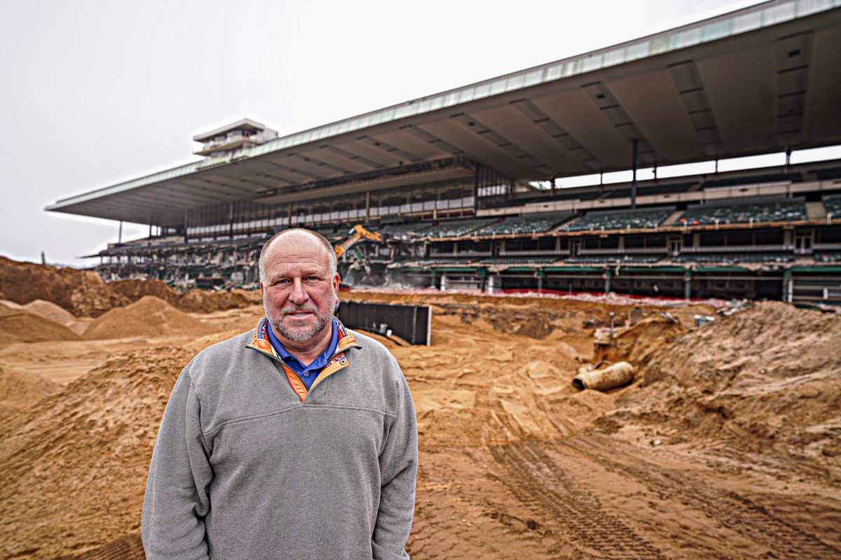 Man standing in front of Belmont Park during grandstand demolition and track reconstruction.