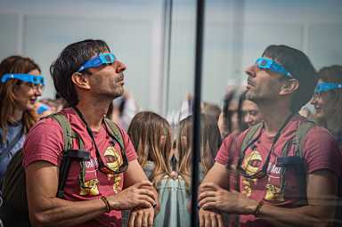 Man in special glasses looks up to watch the solar eclipse
