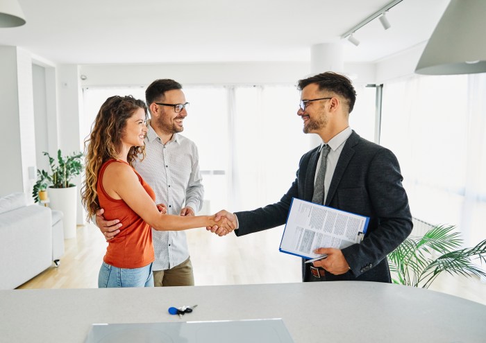 Real estate agent with couple shaking hands
