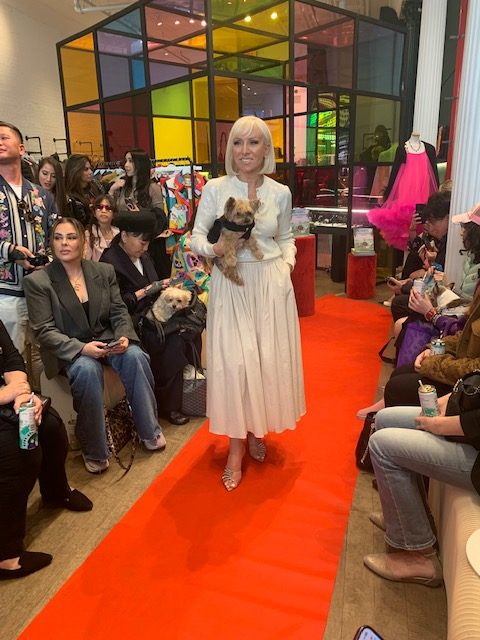 woman holding a small dog on a red carpet during a benefit for dog rescues in SoHo, NYC