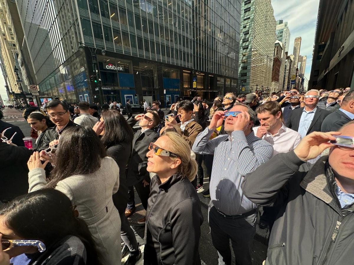 A crowd watches the eclipse at the corner of 42nd Street and Madison Avenue.