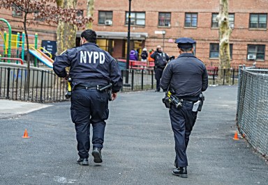 Police officers walk at scene of East Harlem homicide