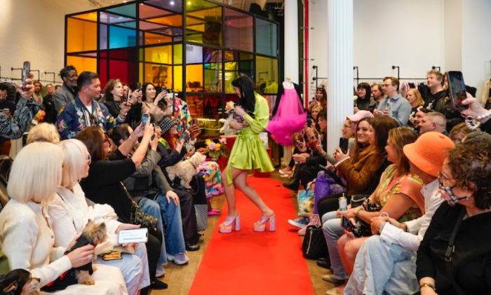 dog and a woman on a red runway at a fashion show.