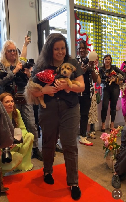 woman holding a dog with other people in the background during benefit for dog rescues