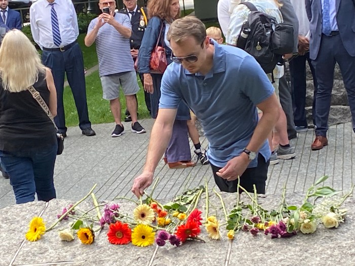 man placing a flower down at 9/11 Memorial in Manhattan