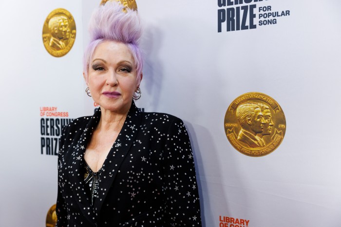 Singer Cyndi Lauper with lavender hair and wearing a sparkly black jacket