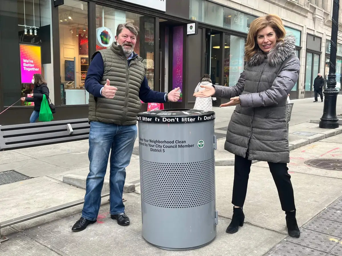 Two people with NYC street trash basket