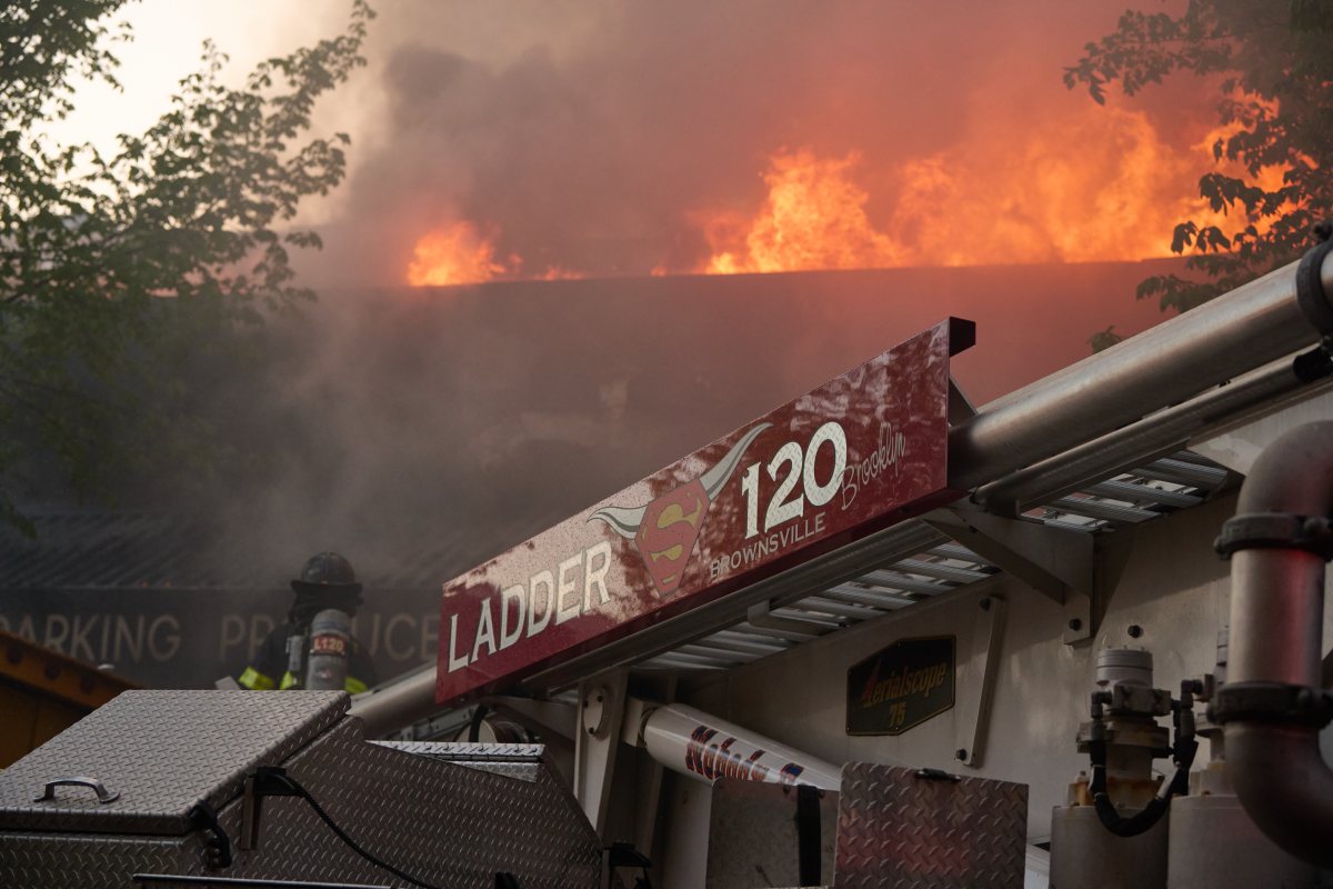 Flames shoot through the roof of a Brooklyn supermarket during a five-alarm fire on May 1, 2024.