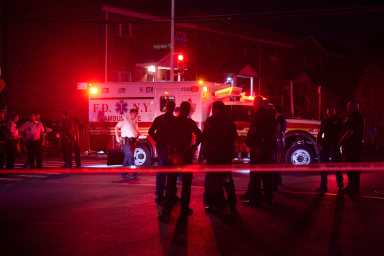 Brooklyn crime scene at night with NYPD officers standing near EMS truck