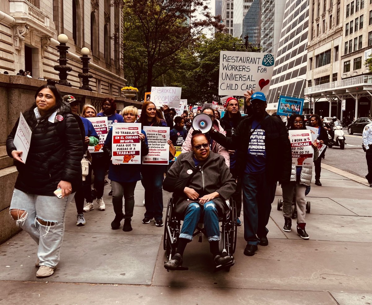 people marching on a side walk in Manhattan holding signs to support child care funding