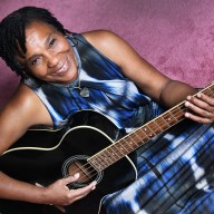 Felice Rosser of FaithNYC holding guitar