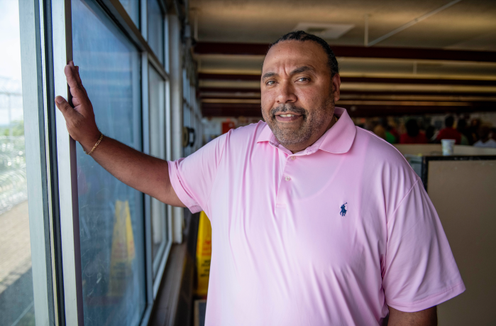 man in pink shirt standing by a window