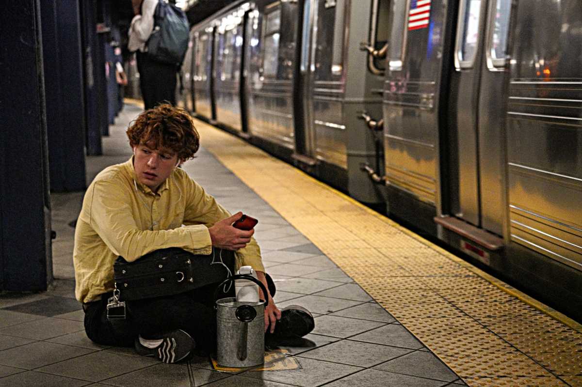 A straphanger sits down on a sweltering subway platform during a heat wave on July 16, 2024.