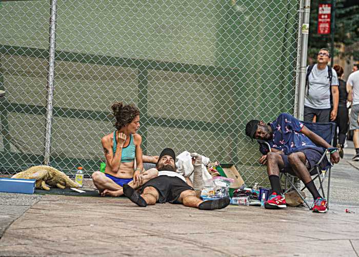 A group of homeless individuals lounge in the sun.