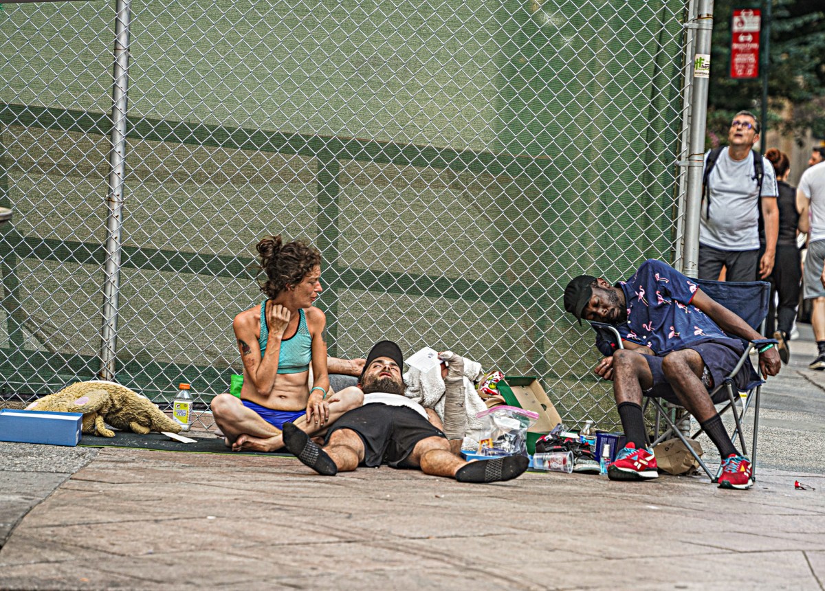 A group of homeless individuals lounge in the sun.