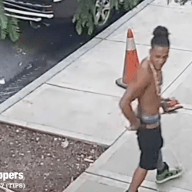 man walking on sidewalk with no shirt on, wanted for assault in Brooklyn