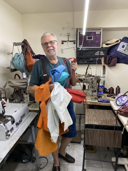 Harlem designer turns practical accessories into wearable works of art 3 man holding up material in a design studio