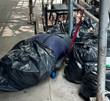 A human body wrapped in trash bags and covered in flies was found Friday on a Kips Bay street, police said.