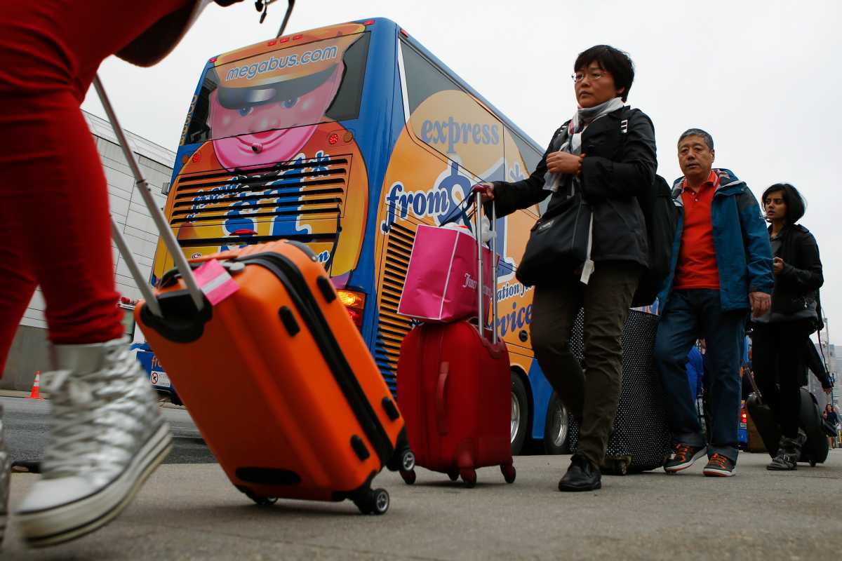 Passengers line up to board a Megabus bus in New York City May 8, 2014.