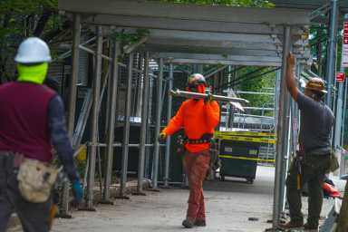 Worker removing sidewalk shed from medical examiner's office