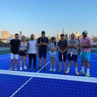 several people, at least most being US Open fans, with Andy Roddick on a tennis court at the Seaport in Lower Manhattan