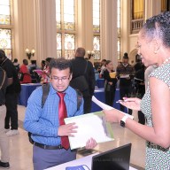 people around a table at in a hall at a NYC career fair