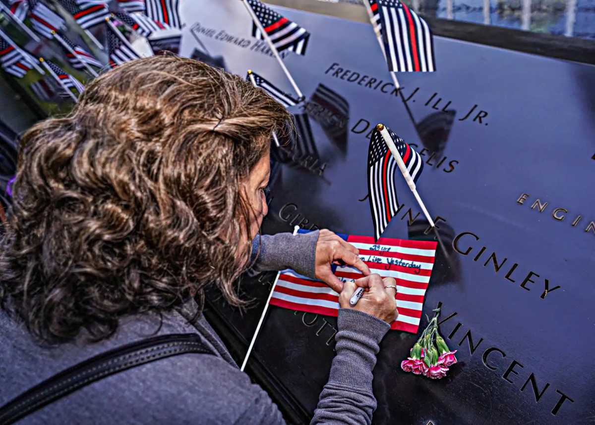 woman at 9/11 memorial writes remembrance on American flag