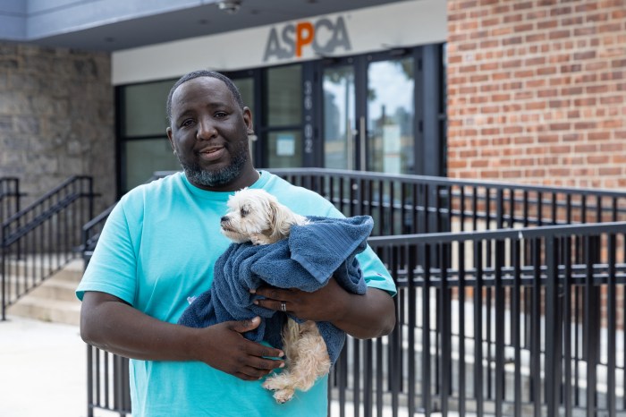 Free ASPCA clinic opens for pets in Queens offer tender loving care from experts 2 man wearing blue shirt holding a dog near ASPCA vet clinic in Queens
