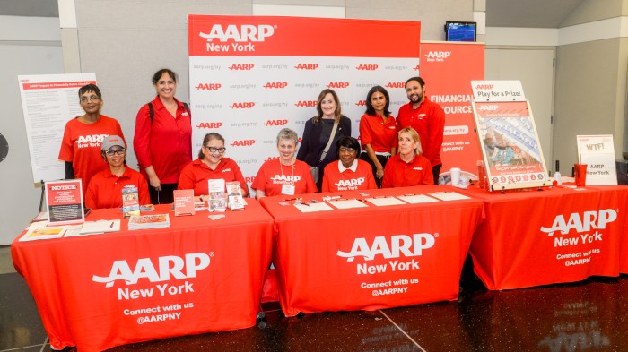 AARP and Schneps Media host financial empowerment event for New Yorkers 2 people at a table with AARP logos and papers on it