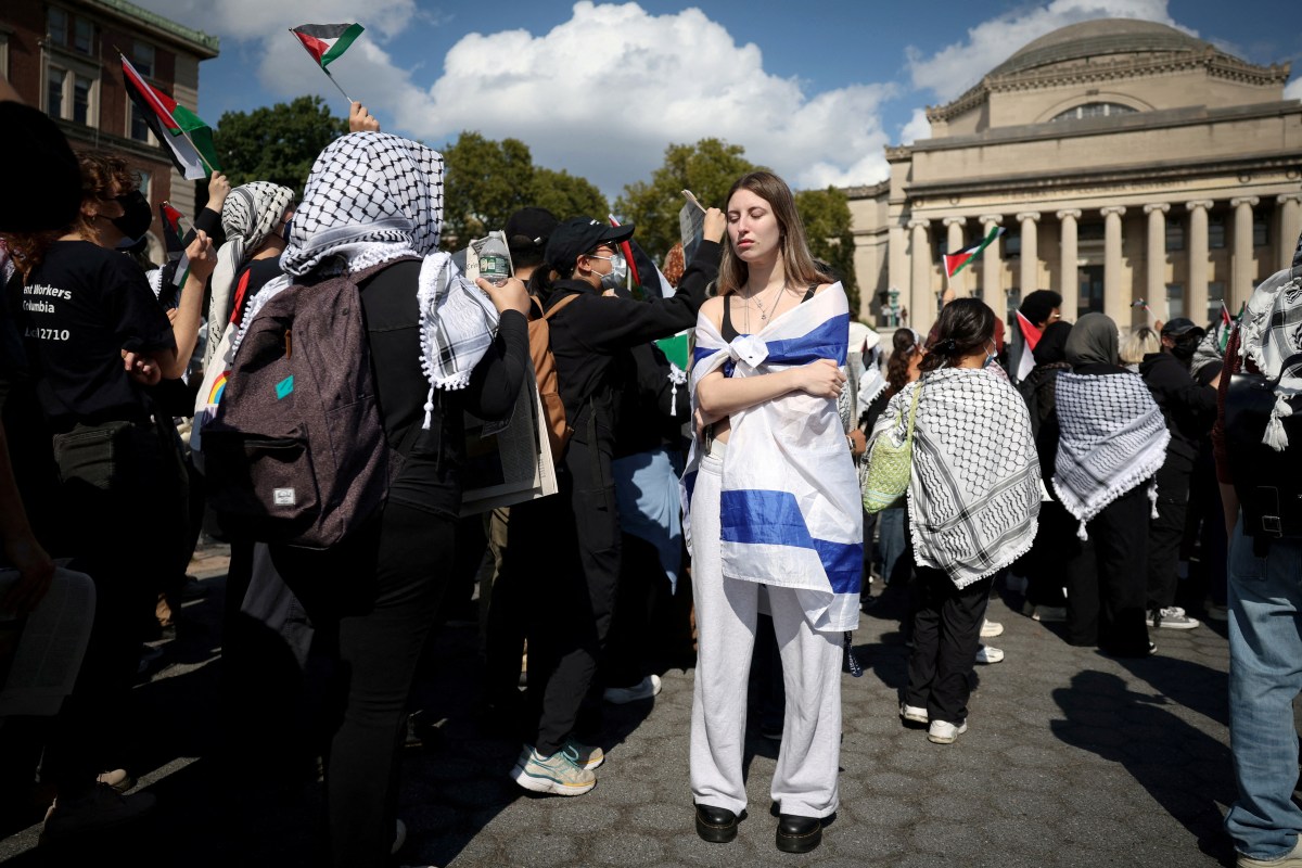 A female student wrapped in Israel flag stands amid pro-Palestinian demonstrators on the campus of Columbia University