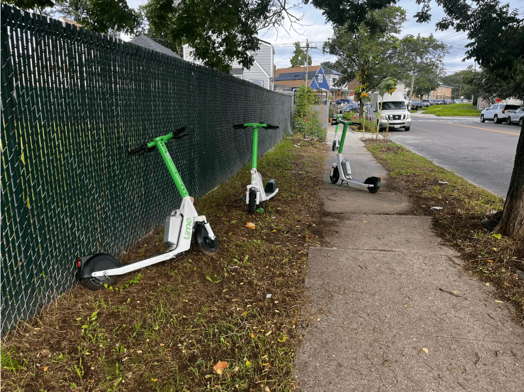 E-scooters left parked on sidewalk and grass
