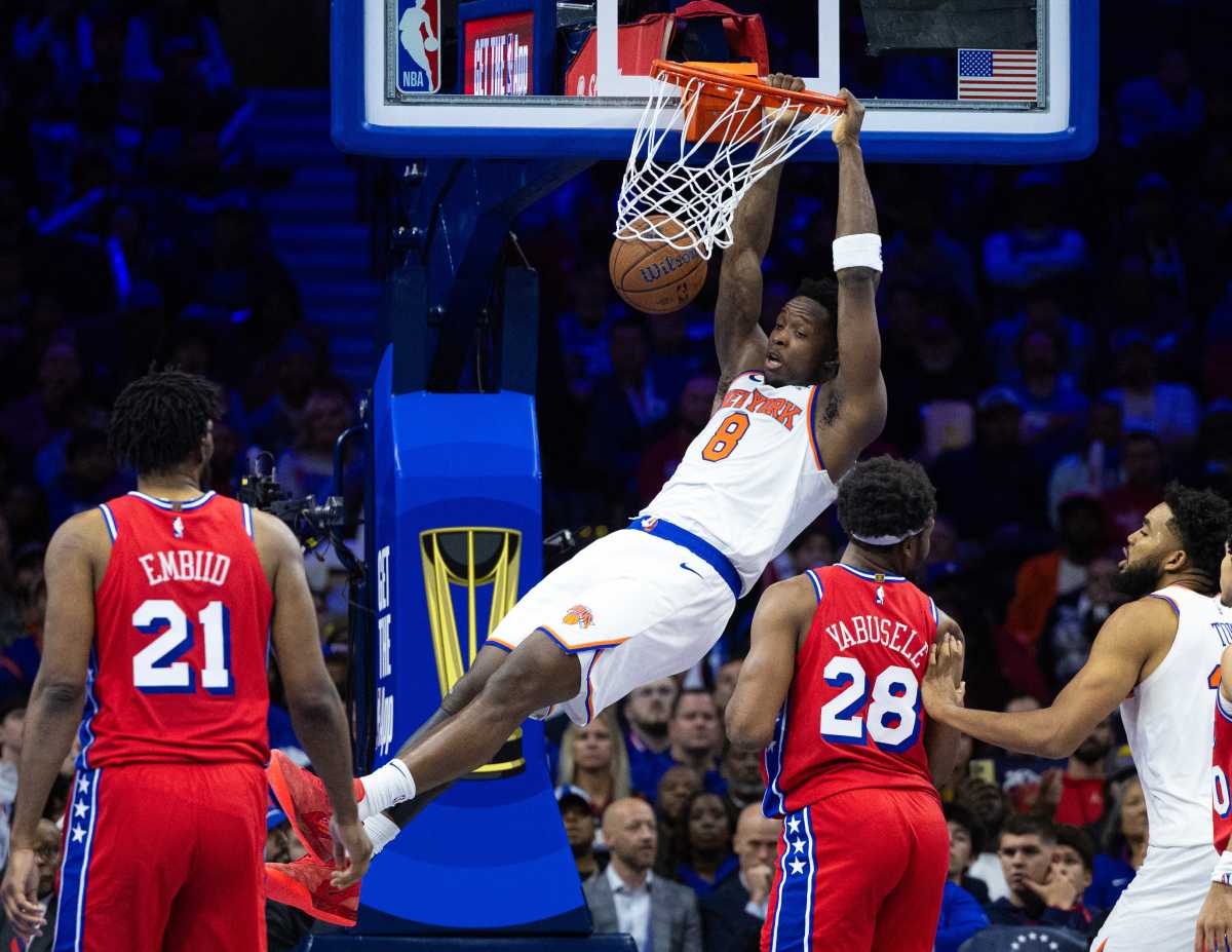 New York Knicks forward OG Anunoby (8) dunks the ball in front of Philadelphia 76ers center Joel Embiid (21) and forward Guerschon Yabusele (28) during the fourth quarter at Wells Fargo Center.