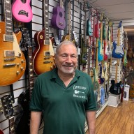 Castellano's House of Music: A music store in tune with NYC for over 50 years 5 man in front of a row of guitars on a wall inside Castellano's House of Music, a music store in NYC