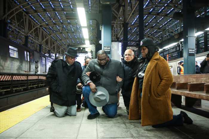 Rev. Kevin McCall and other advocates kneel on the F train platform at the Stillwell Avenue-Coney Island station on Dec. 26, 2024 for a vigil to honor the woman who was burned alive at the station four days earlier.