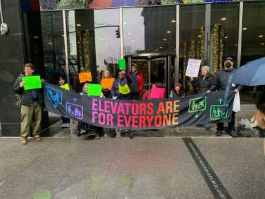 New Yorkers protest outside MTA headquarters in Lower Manhattan advocating for better subway accessibility.