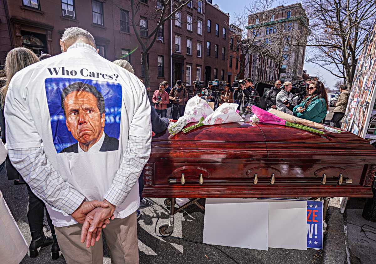 COVID memorial in Brooklyn with casket and guy wearing shirt with photo of Andrew Cuomo