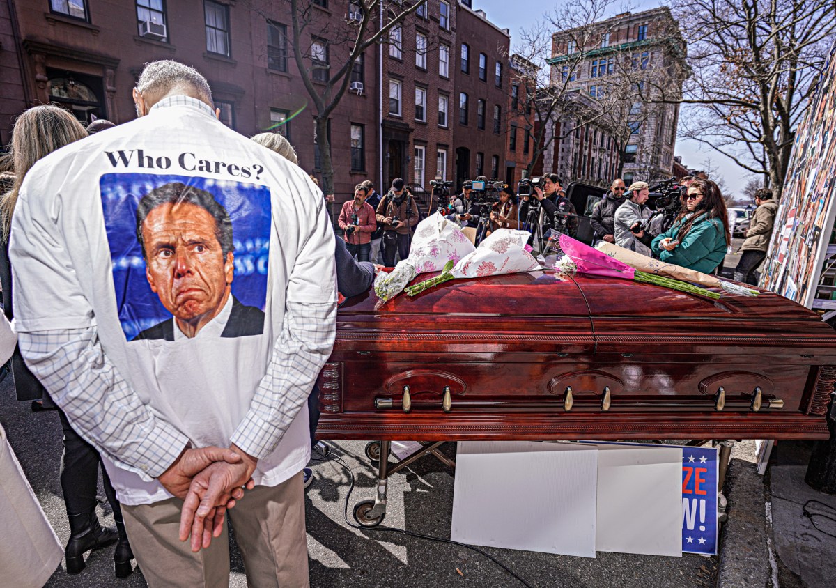COVID memorial in Brooklyn with casket and guy wearing shirt with photo of Andrew Cuomo