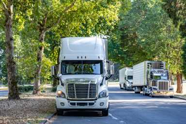 Line of trucks parked on tree-lined street