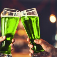 Two friends toasting with glasses of green beer at the pub with free space for your text. Beautiful background of the Beer Fest and St. Patrick's day. fine grain. Soft focus. Shallow DOF