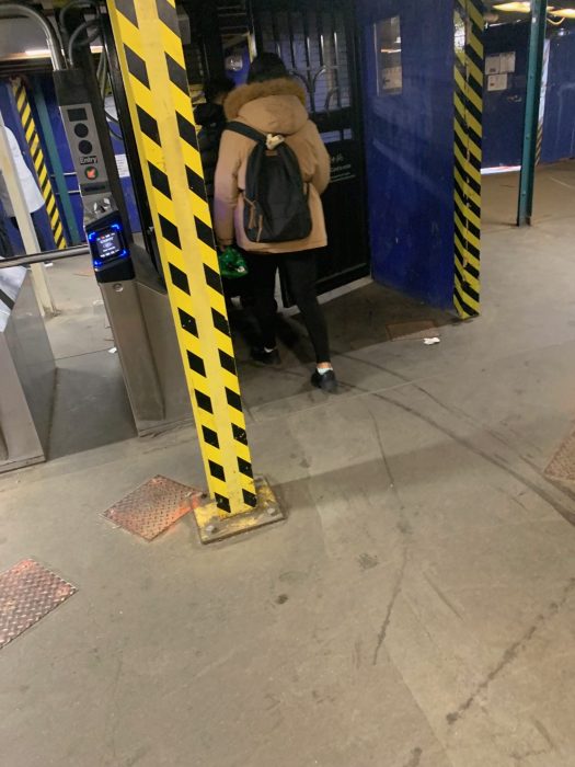 People walking through automated gates in a Queens subway station. 