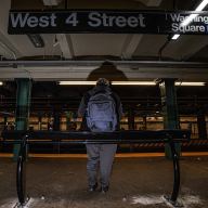 West 4th Street subway station with people leaning on metal bars