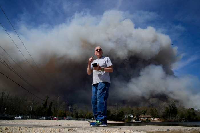 Man stands in front of smoke amid air quality alert from New Jersey wildfire